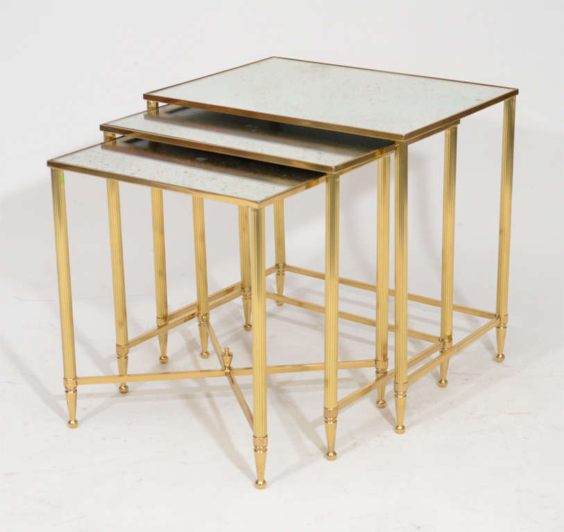 Stunning set of decorative modern polished brass nesting tables with antiqued finished glass.  Located in Las Venus at ABC Home.