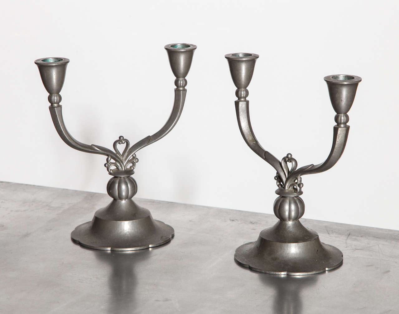 Pair of Just Andersen 6002 Two Arm Pewter Candlesticks, 1929.  Featuring Crest details in Satin Silver finish on circular scalloped base. Sculptural. Art Deco. Rarity. Signed JUST 1929 DENMARK 6002 