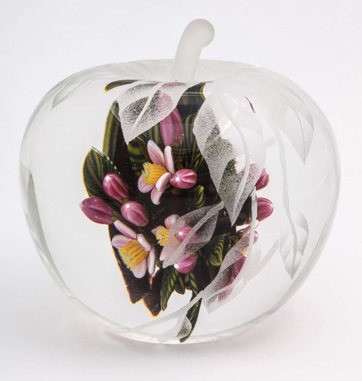 A beautiful Cathy Richardson sandblasted apple paperweight sculpture, the inside with pink flowers, buds and striped leaves and the outside carved with a leaf pattern