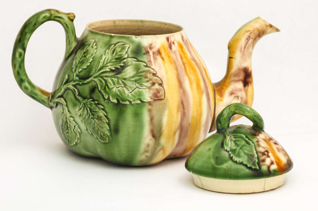A rare and fine English creamware pottery, Whieldon school, teapot molded in the shape of a pear, with riased leaves and decorated in underglaze oxide colors of yellow, green and brown