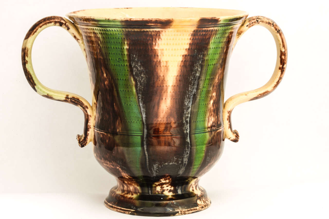 A fine English creamware pottery loving cup, Whiedon school, decorated in underglaze oxide colors of green and brown