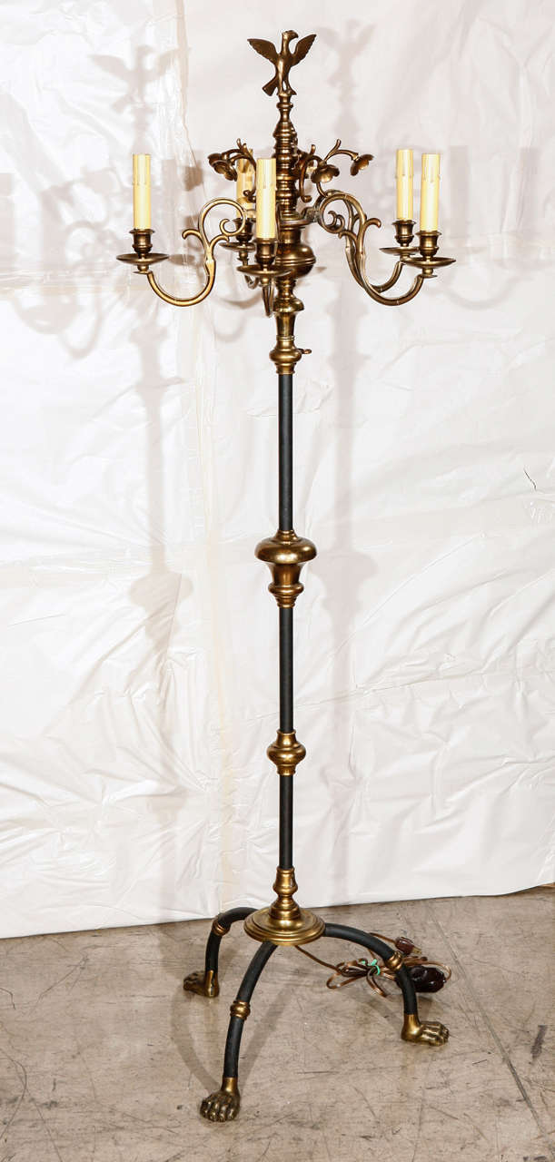 A spectacular Hollywood Regency floor lamp decorated with an eagle finial, floral flourishes and highly detailed paw feet. Floor lamp is heavy and substantial and has five light bulb sockets.