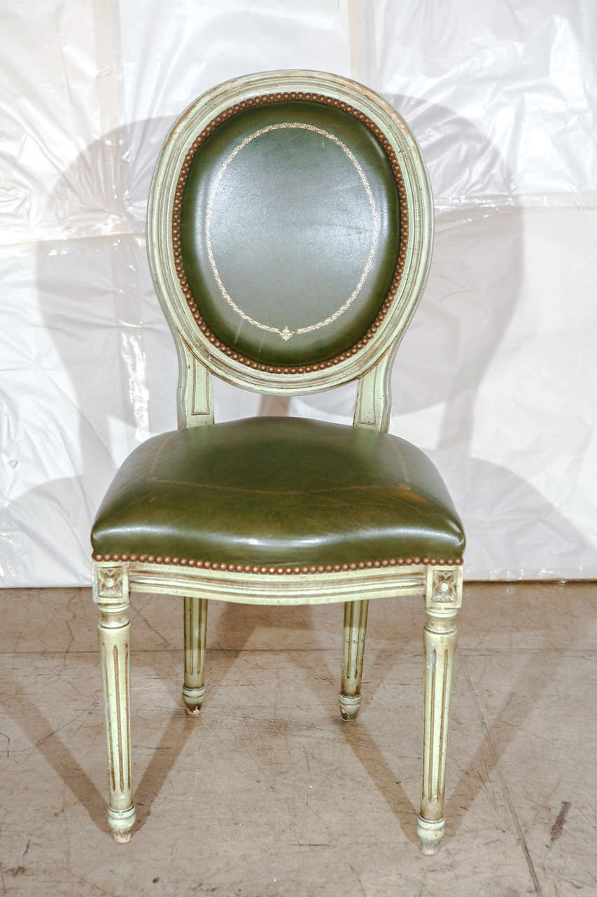 An impressive set of six Louis XVI style dining chairs with original green leather. Leather seats and backs are detailed in a gold embossed vine design.