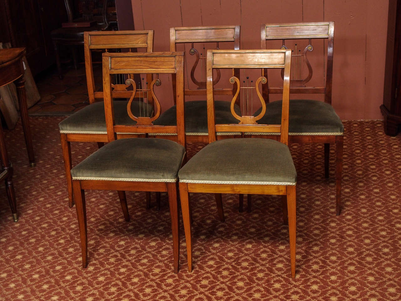 Set of ten 19th century French Directoire style dining chairs with sabre legs and lyre decoration at back, accented with bronze rosettes