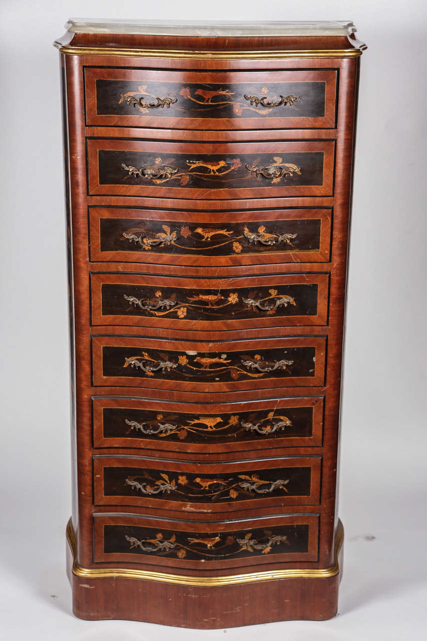 The front of this chest is serpentine. Inlaid flowers are on each drawer and sides. This comes with a beveled marble top and is in two tones of wood with brass handles.