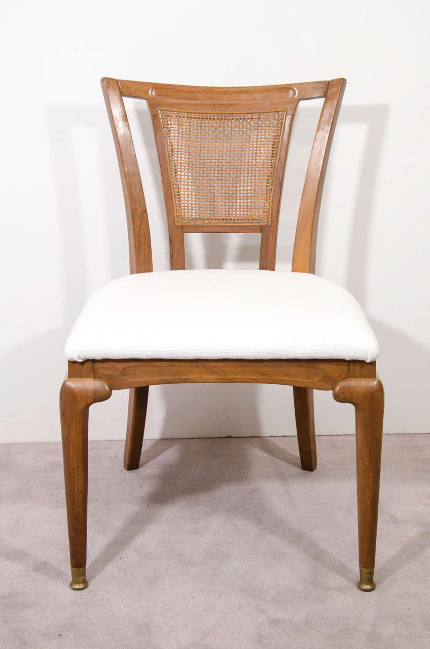 A vintage pair of teak side chairs, with white linen seats and cane backs.