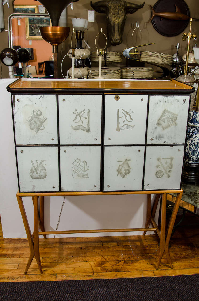 A vintage bar cabinet with etched panel scenic exterior and an illuminated mirrored interior. Each tile has a 