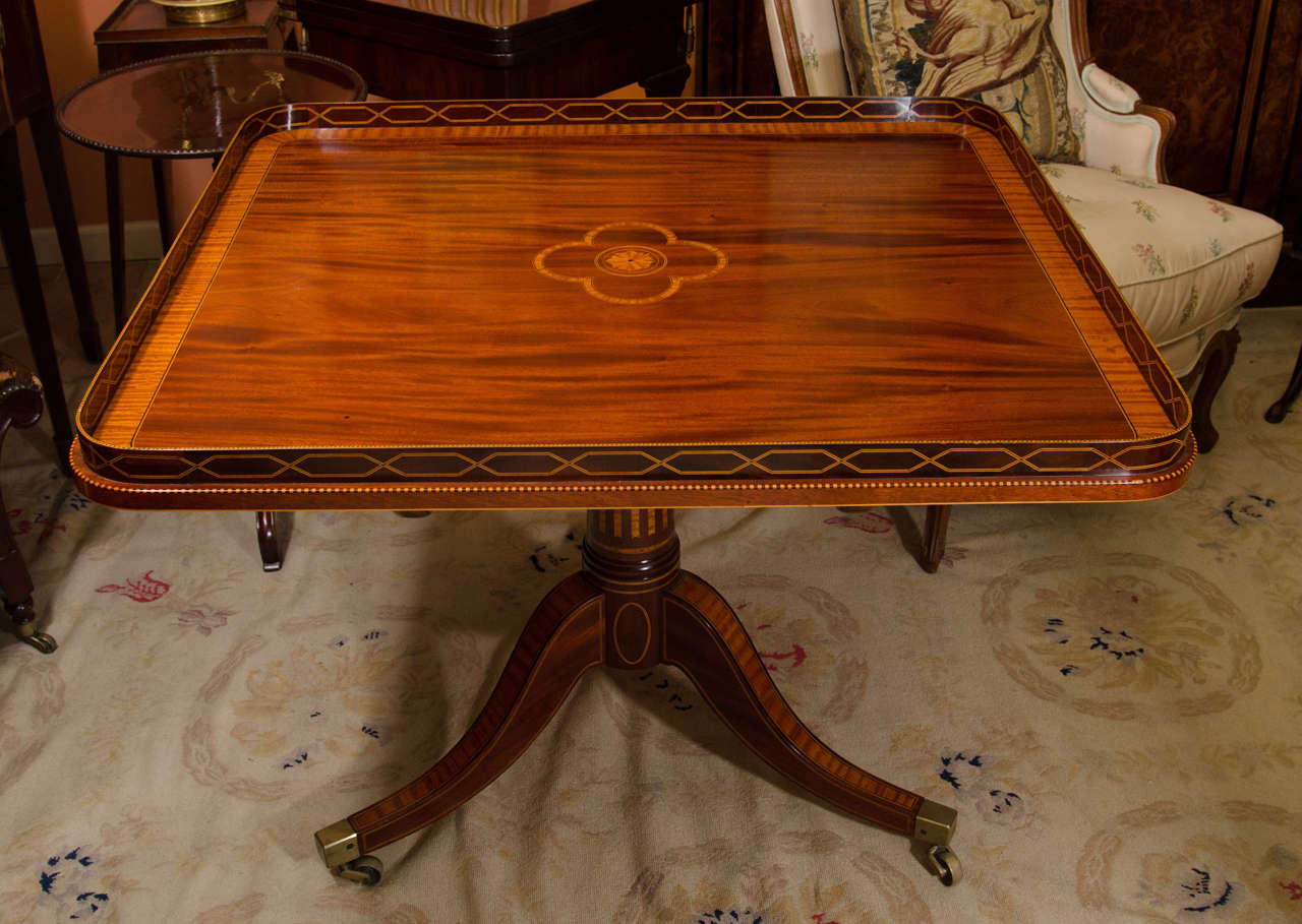 A rare and very fine Regency mahogany tilt-top square centre table with satinwood inlays and crossbanded on an inlaid pedestal with brass casters.