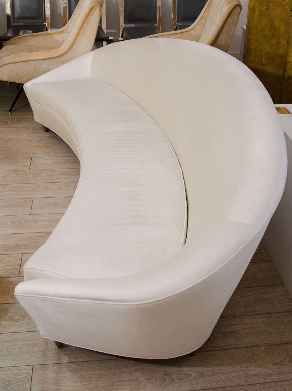 Upholstered curved sofa with brass feet amd tight back attributed to Ico Parisi.