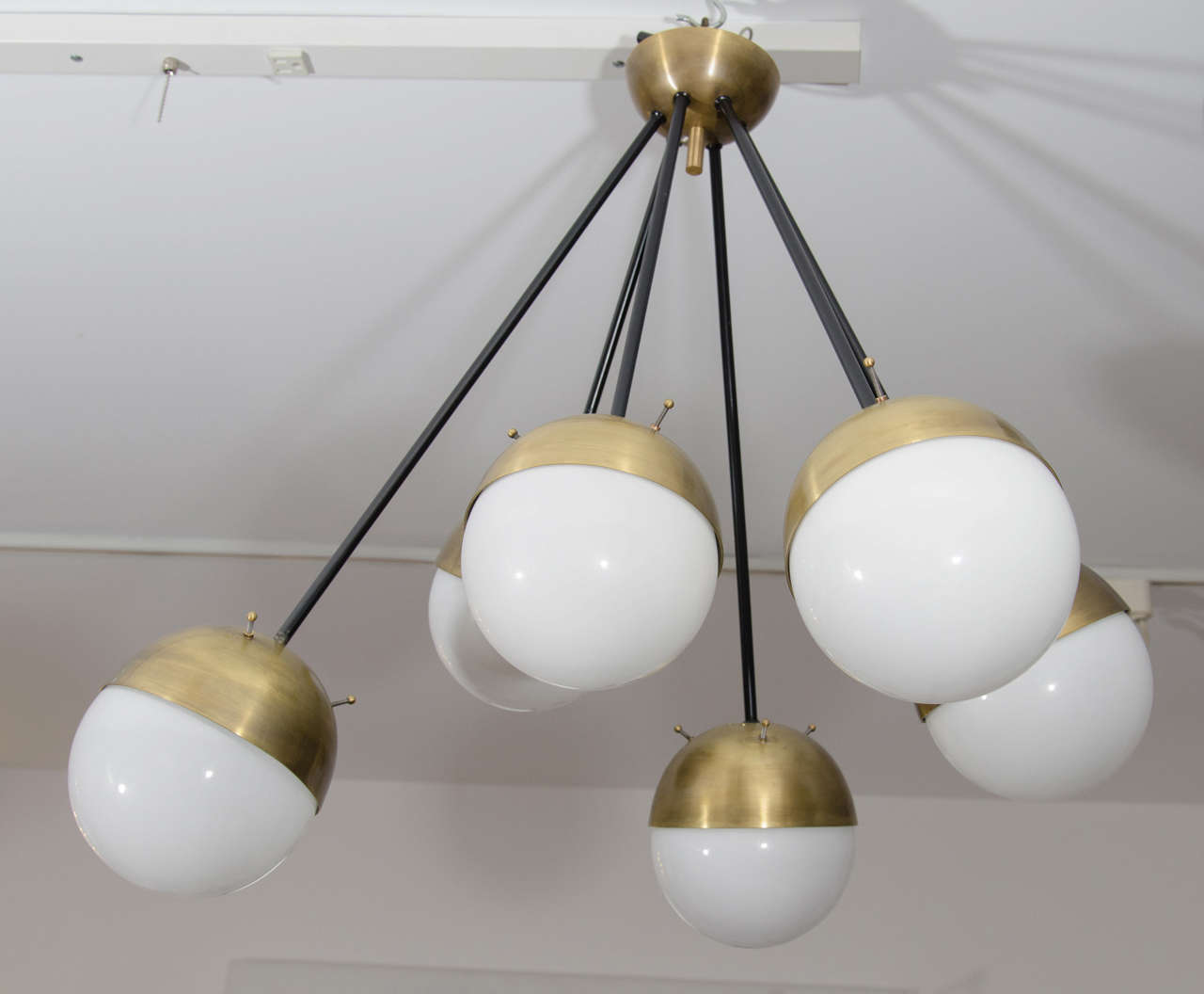 Multi length brass and glass chandelier by Stilnovo. Restored brass with black powder coated stem and original glass shades. The glass orbs are 7.5