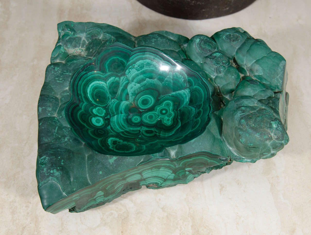 A solid piece of organic Malachite with a shallow bowl carved in the center.