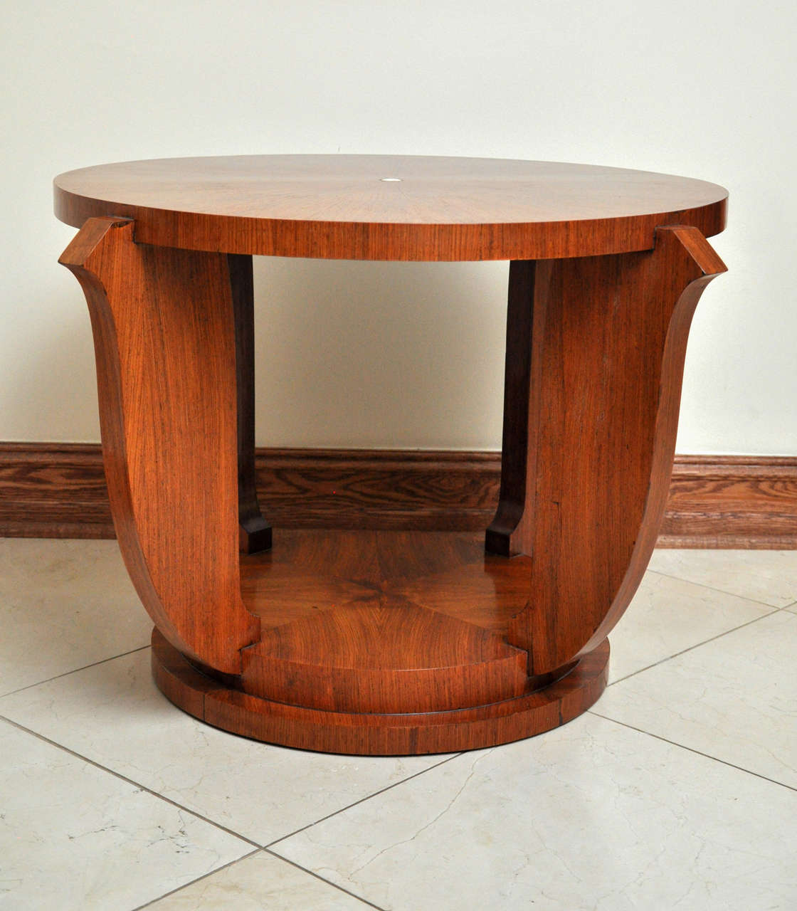 An exceptional example of Art Deco design attributed to Jules Leleu, this table features a well-figured starburst rosewood veneer, contrasted by a mother-of-pearl inlay accent. Its circular top is echoed on the stepped, round base. The supporting