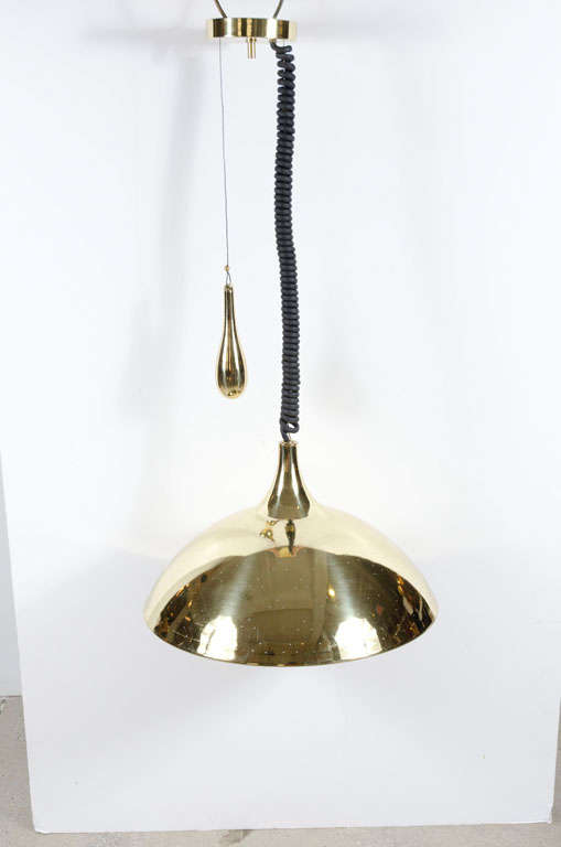 The 'Finlandia', mod. no. 214, a pendant light comprising a perforated polished brass dome shaped ceiling fixture with counterweight and opalescent glass diffuser. Measurements: Adjustable height from 38 to 48 inches. After Paavo Tynell. By