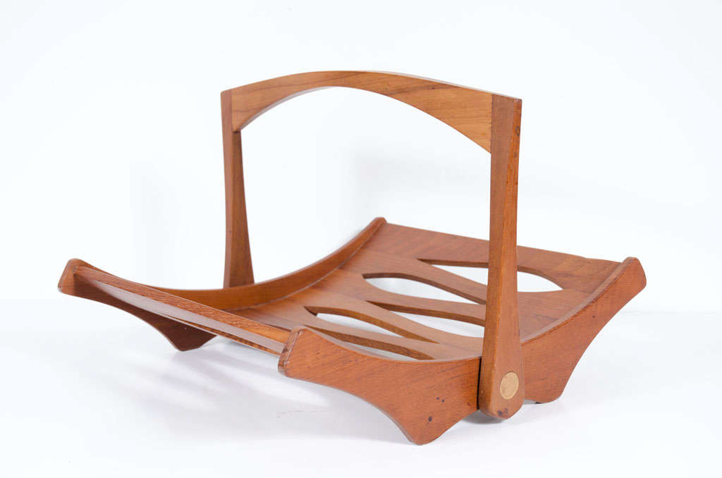 A beautiful staved teak magazine rack with moveable handle and cut-out forms to the body. Branded [Staved Teak IHQ Danmark]. Designed by Jens Quistgaard. Denmark, circa 1960s.