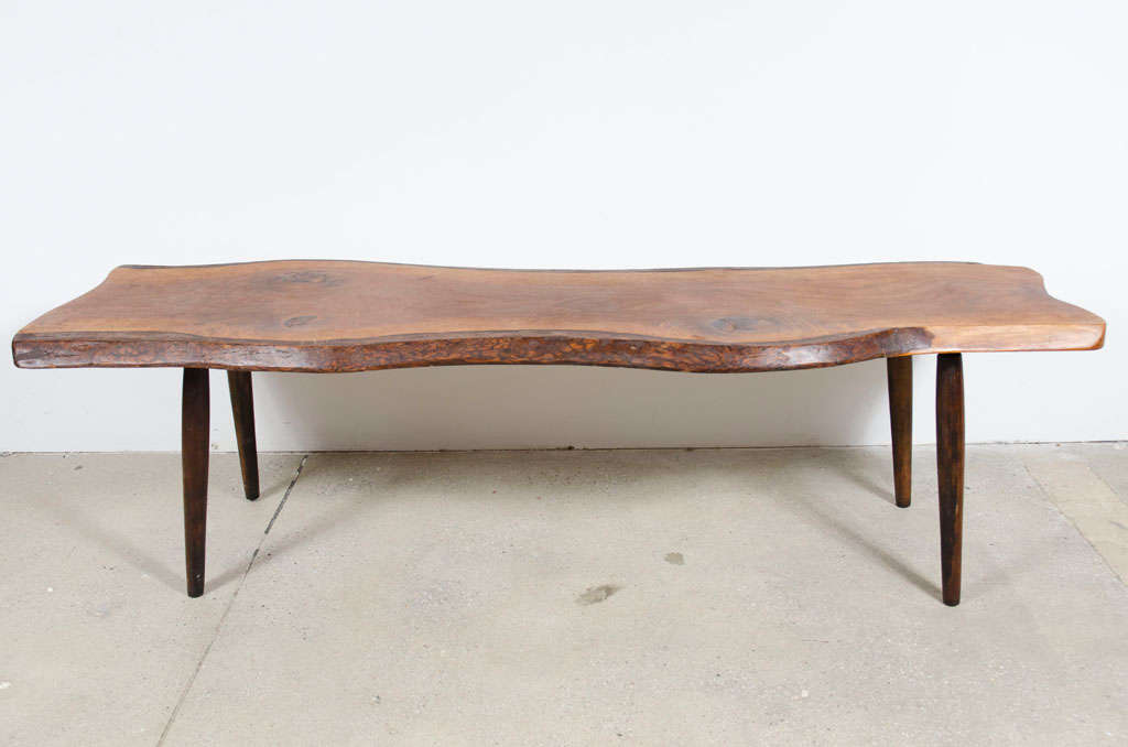 A beautiful America Studio Craft coffee table with a serpentine form free edge slab of walnut supported on four turned legs. Signed to the underside. By Roy Sheldon. U.S.A., 1968.