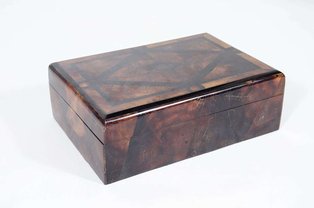 A jewelry box comprising a faux tortoise shell and craquelure lacquer exterior in a geometric design with a black velvet lined interior.  American, circa 1960.