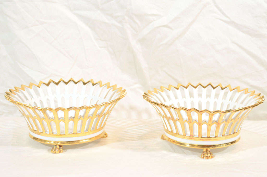 An elegant pair of pierced Paris Porcelain arcaded baskets(corbeilles) heavily gilded, round, with a circular band of white porcelain they stand on lion's paw feet.