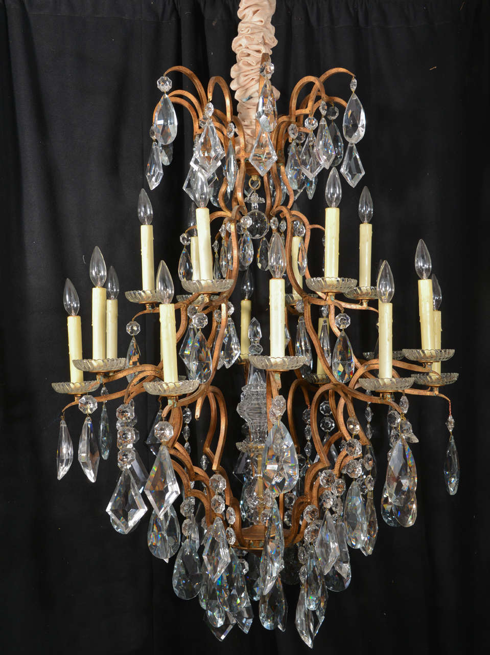 Eighteen-light French, Versailles style chandelier, featuring beautiful large crystals in various shapes with ivory wax candle covers and cut crystal bobeche. Metal is gold leaf over iron.