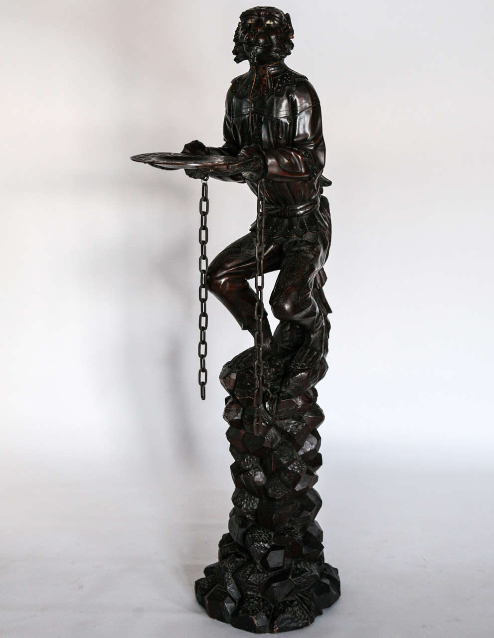 Carved walnut in the form of a monkey with an attached tray and wood chain, seated on a rock work base.