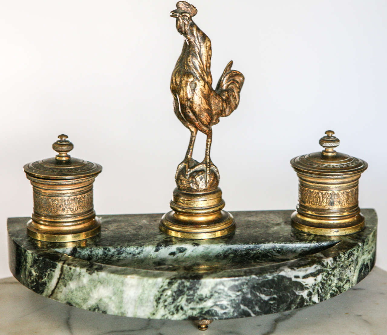 Marble inkwell adorned with removable bronze rooster and two hinged top inkwells with glass liners. Bronze feet. Remnants of gilt overlay.