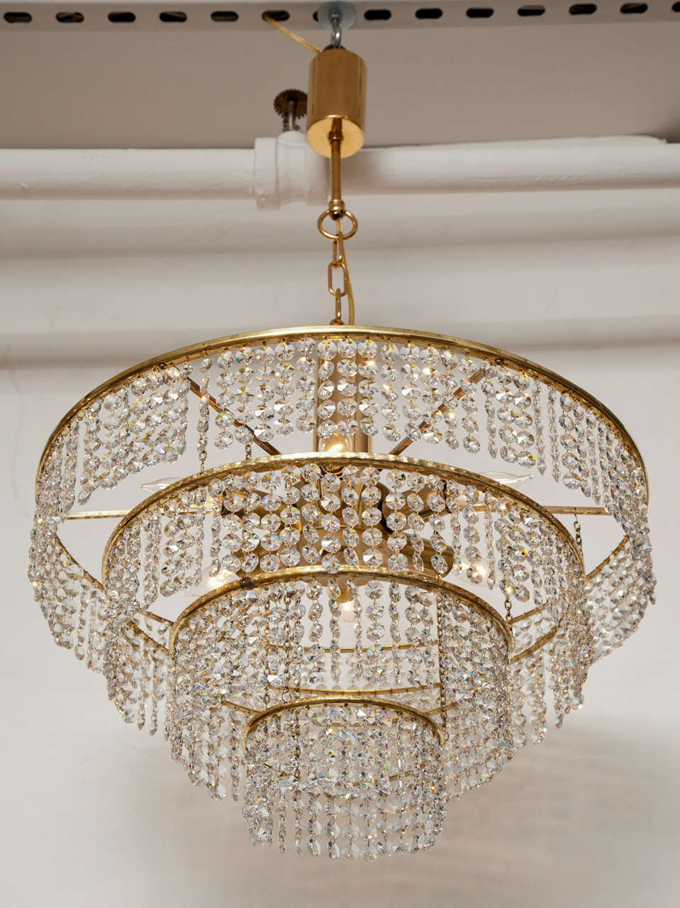 A lovely chandelier in brass and 24-karat gold plate with four tiers of sparkling crystals, circa 1950, from a German hotel.