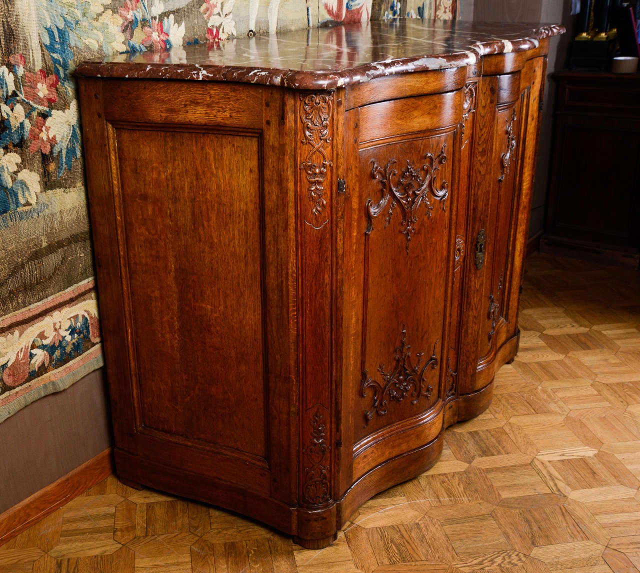 A French Régence carved oak buffet with scrolling foliage, opening by two doors. Red marble top.