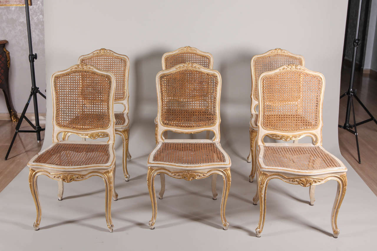 Ensemble de six chaises françaises du XIXe siècle en ivoire peint et doré à la feuille  avec des sièges cannés.