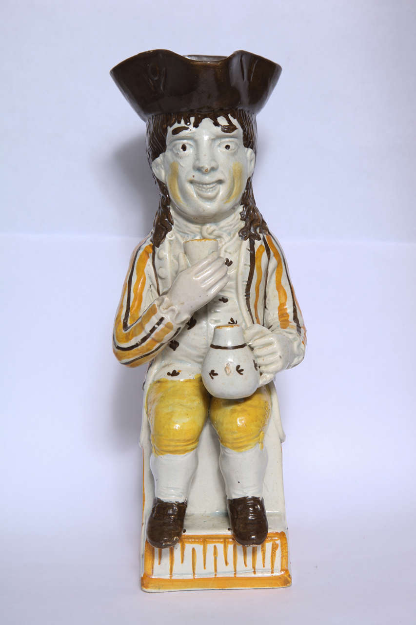 A rare English pearlware pottery Thin Man toby jug decorated in underglaze Pratt colors of yellow, orange and brown