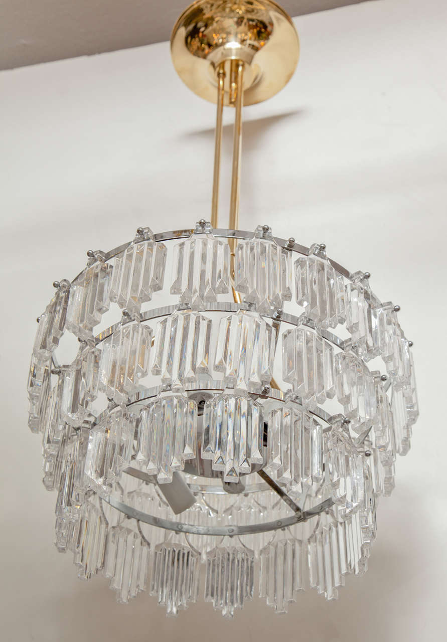 Swedish Modern three-tier crystal chandelier suspended from a brass and nickel armature by Orrefors. Rewired for use in the USA, using six candelabra type bulbs. 

Currently a pair is available..