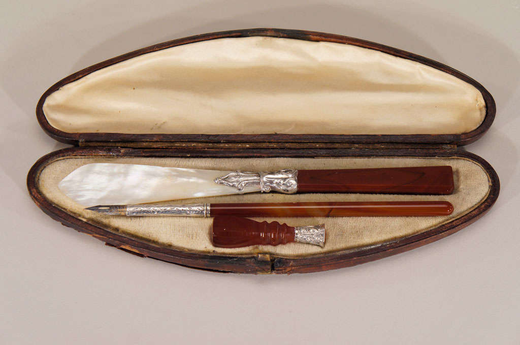 This lovely three-piece 19th century writing set consists of a pen with silver tip, letter opener of mother of pearl with agate handle and silver connector and a detailed intaglio engraved seal. Each piece fits into the oval shaped leather box and