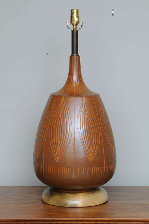 Wonderfully organic in form with a Sgraffito design on the surface of ti leaves or cacoa pods, this large Mid-Century table lamp was created by George Nobuyuki Kimura and offered by his firm, Sy Allan Designs of California. A large bulbous form, it