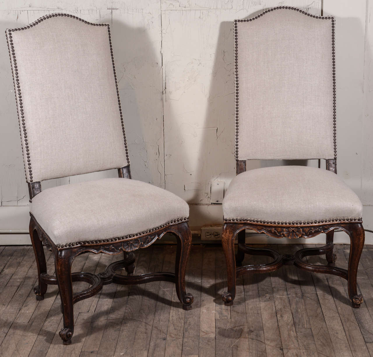 Pair of Regence side chairs hand carved in oak, mid-19th century, France. Adorned by carved rocaille (shell and sinuous foliate forms) motifs. Each seat is framed by a shaped apron atop four cabriole legs, supported by a curved cross stretcher
