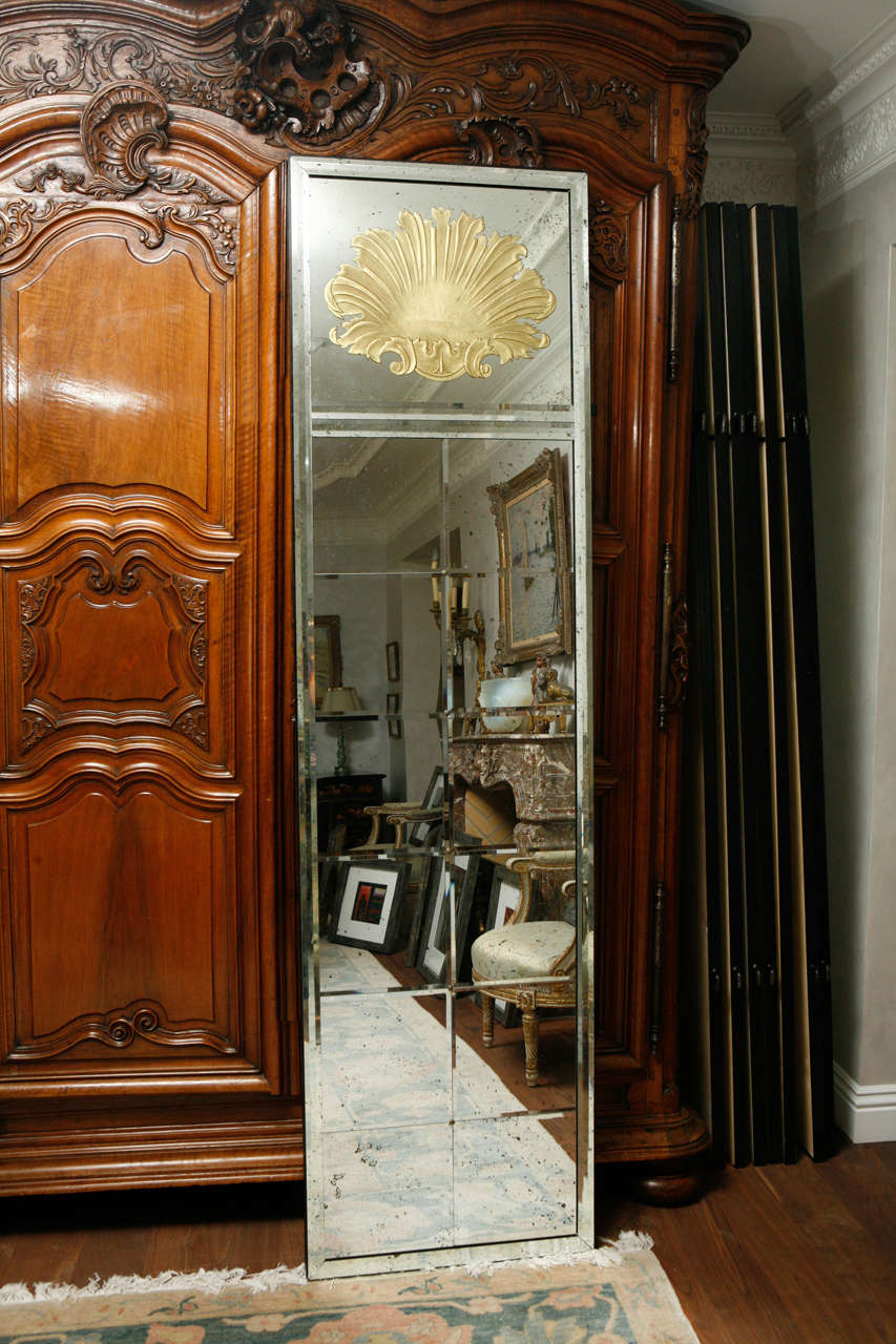 Pair of églomisé gilt etched glass mirrored panels with shell motif from the mid-20th century. Each one has a shell above 12 beveled and distressed mirrored panels. They are reputedly from the collection of Helena Rubinstein. The panels are sold