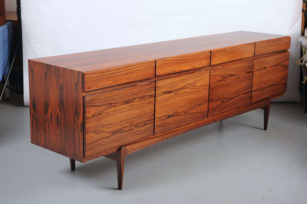 Rosewood sideboard, model 66, front with four drawers and four doors enclosing retractable trays and shelves. Doors with concealed handles. 