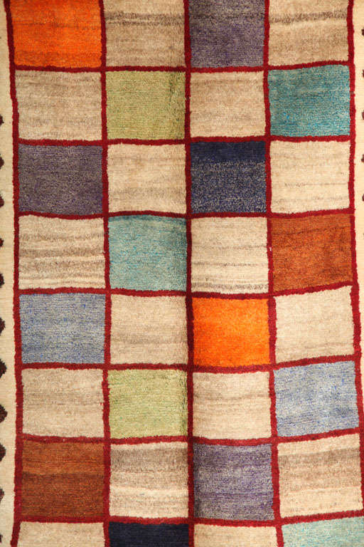 This one-of-a-kind 1940 Gabbeh rug consists of a handspun wool warp and weft as well as a hand-knotted pure handspun wool pile. The design is improvisational and exudes a contemporary feel for a Gabbeh of this period. The pile consists of both