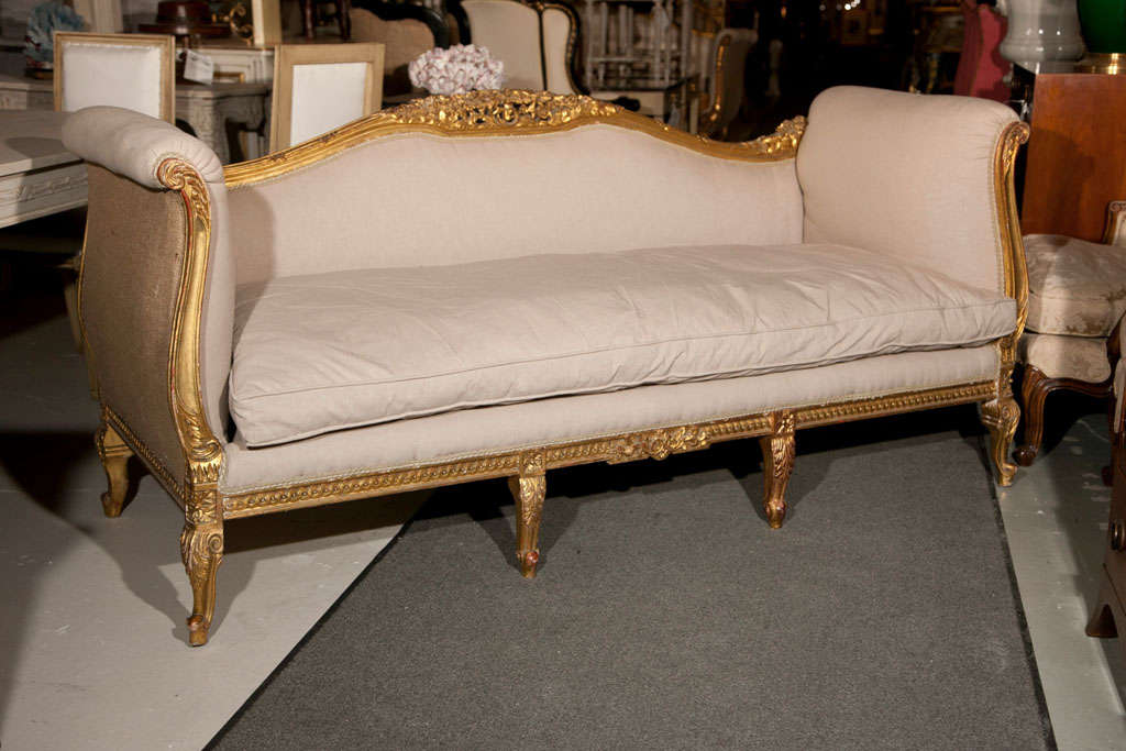 French Louis XV style giltwood sofa or canape, beautiful wood frame in original gilding, serpentine shaped back centered by a pierce-carved crest, rolled arms, upholstered in linen interior and burlap surround exterior, cushioned seat, raised on