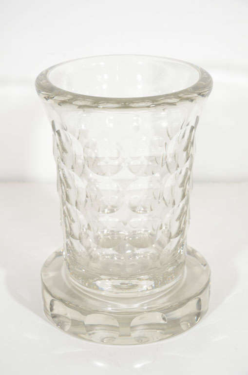 This sophisticated Art Deco crystal vase was realized by the renowned designer Jean Luce, circa 1930. It features a bell-shaped body, a round base that extends beyond the perimeter of the body, and a repeating circular design etched throughout.