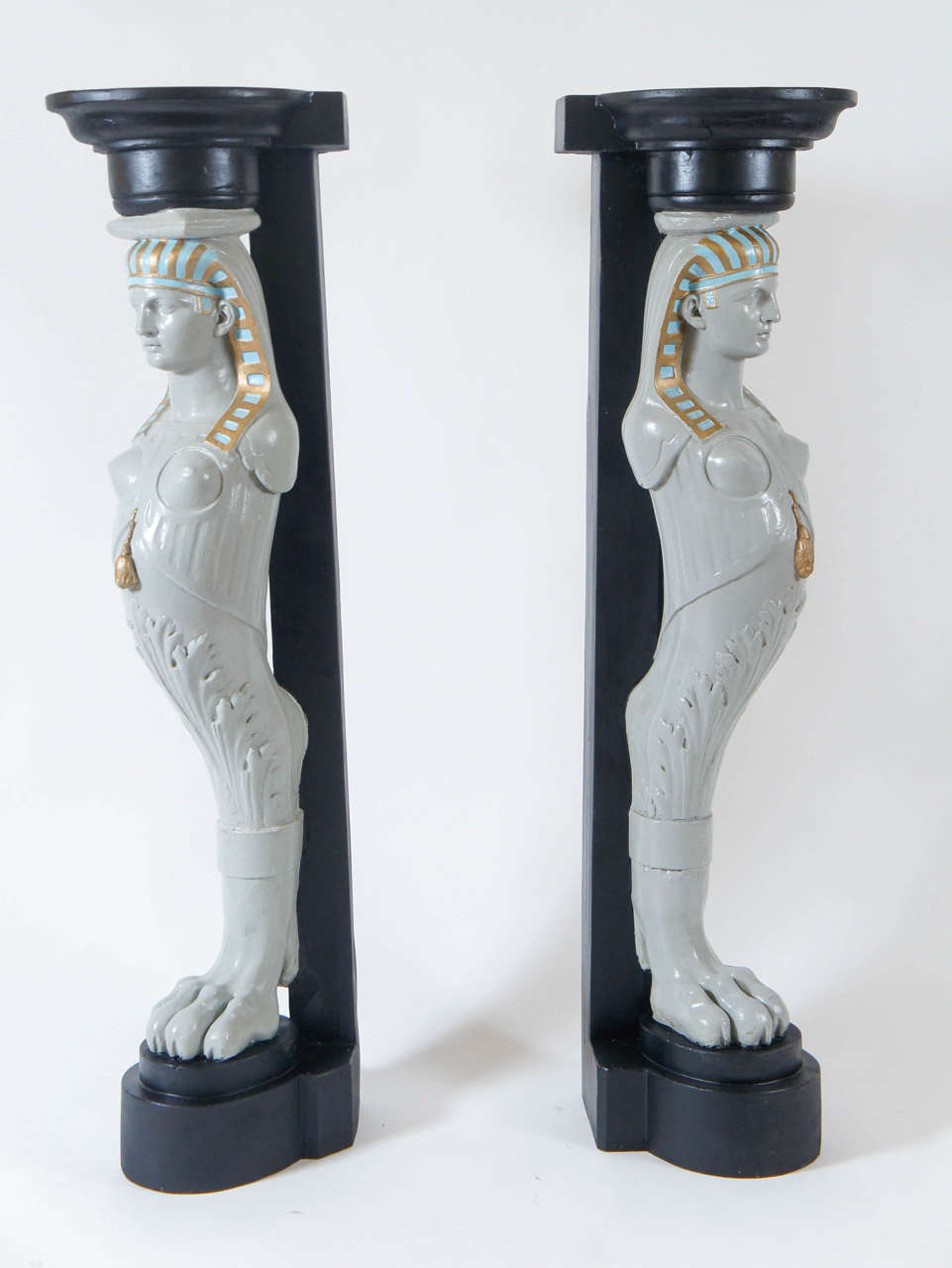 Egyptian Revival style corner pedestals having polychrome painted female pharaoh form terms. Provenance available upon request.