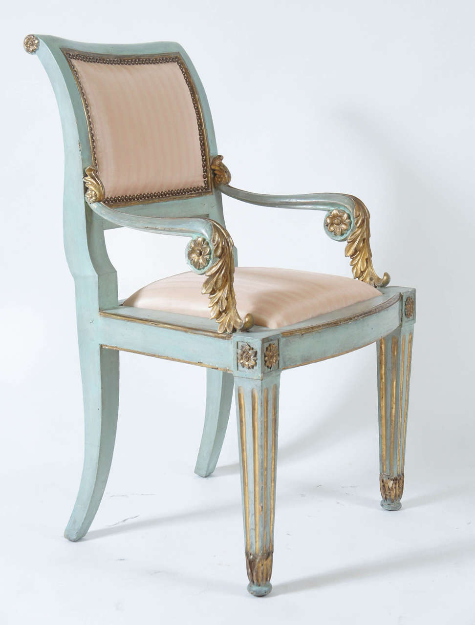 Set of six Italian parcel-gilt and painted armchairs of neoclassical form having upholstered backs and seats with acanthus and rosette carved arms and square fluted tapering front legs with rosette corner blocks below bow- front seat rail. 