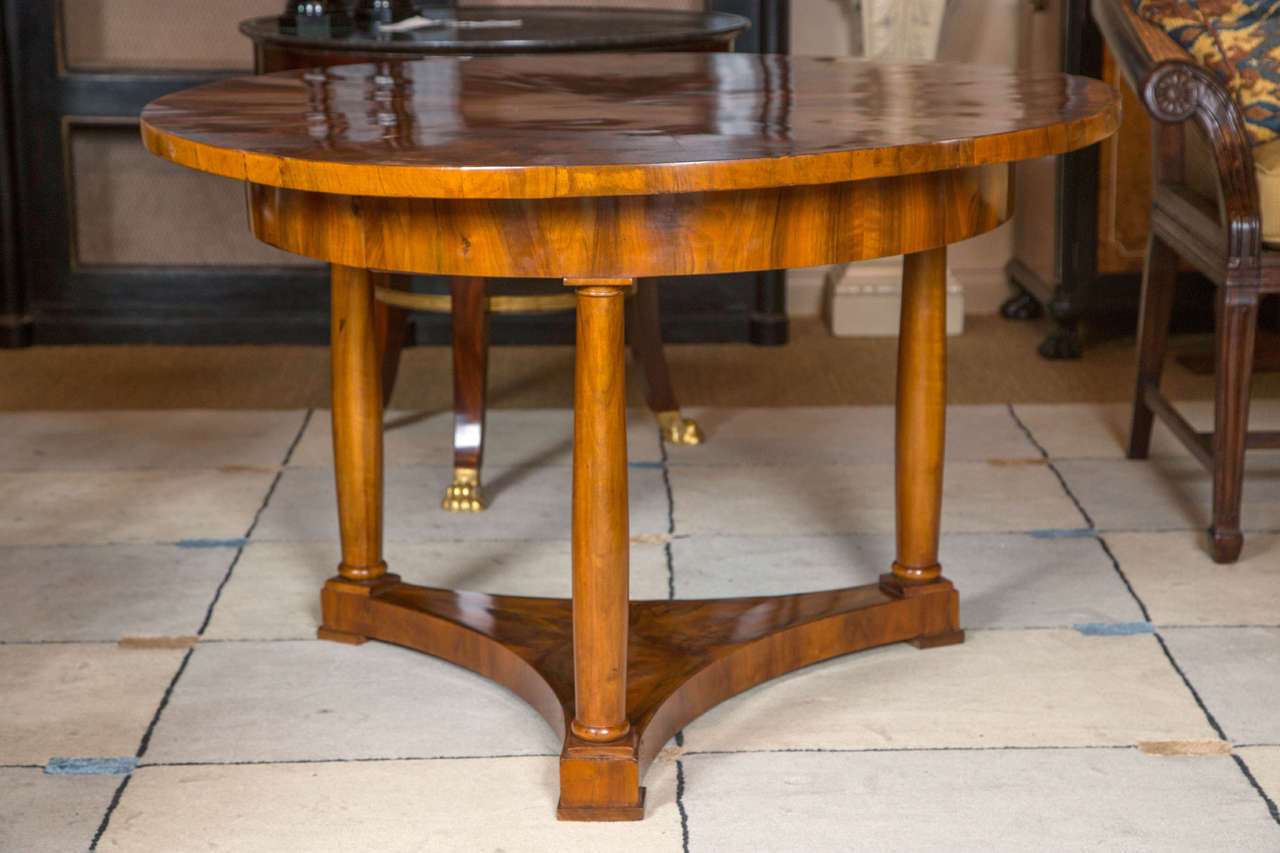 A walnut Biedermeier round center table on three shaped columnar legs having beautiful figured wood.