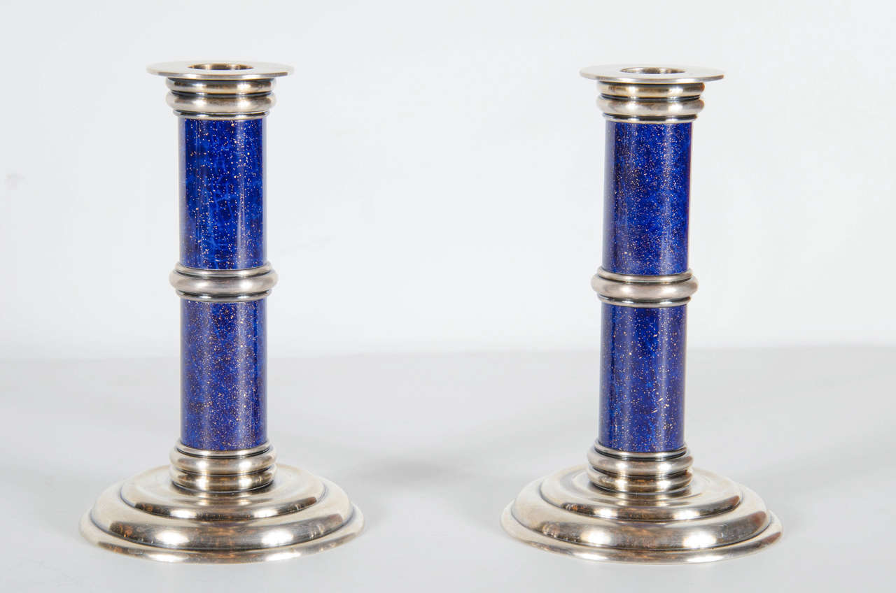 These very sophisticated candleholder are by the renown master silversmiths Puiforcat. They are made of heavy silver-plate with an inlay of lapis lazuli. They feature a stepped skyscraper style circular base with concentric circular banding details.