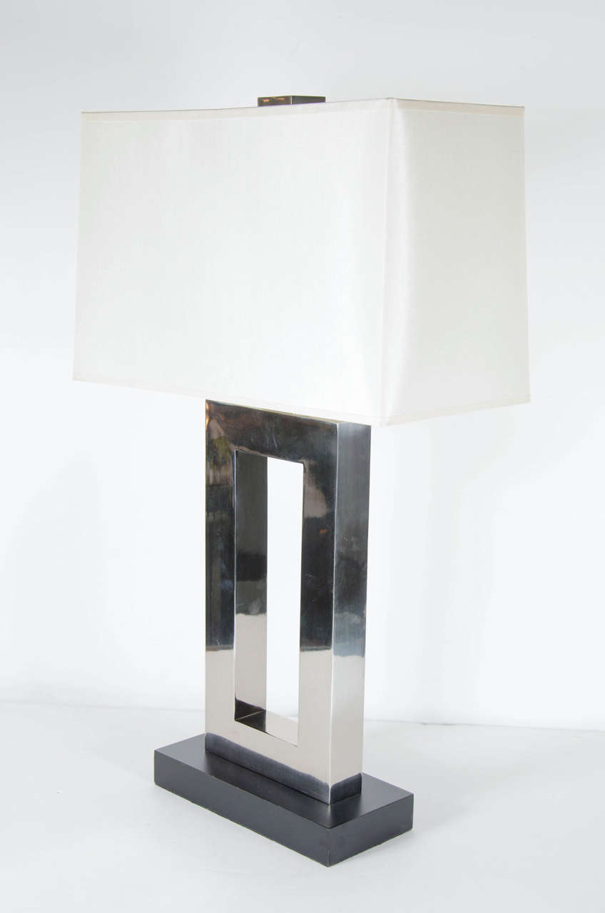 These great table lamps feature a cutout chromed rectangular form design on a stepped black enamel base. They have been newly rewired and feature custom rectangular shades.