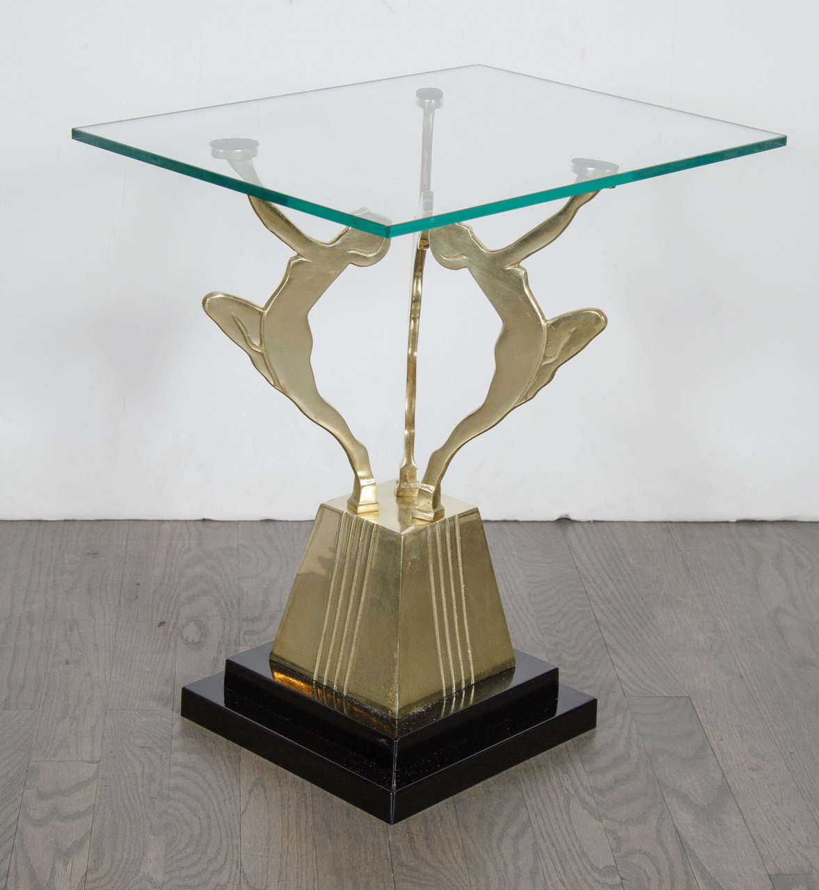 This brilliant Art Deco side table features three Art Deco figures made of solid brass supporting a glass top on a stepped skyscraper style black enamel base. This is a great accent piece in any room.It is in mint restored condition .