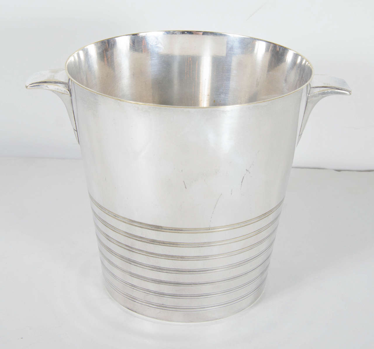 This stunning bucket features handles with a stepped Art Deco skyscraper design and concentric banded detailing. This bucket is silver-plated and bears the mark Perrin on the bottom.
