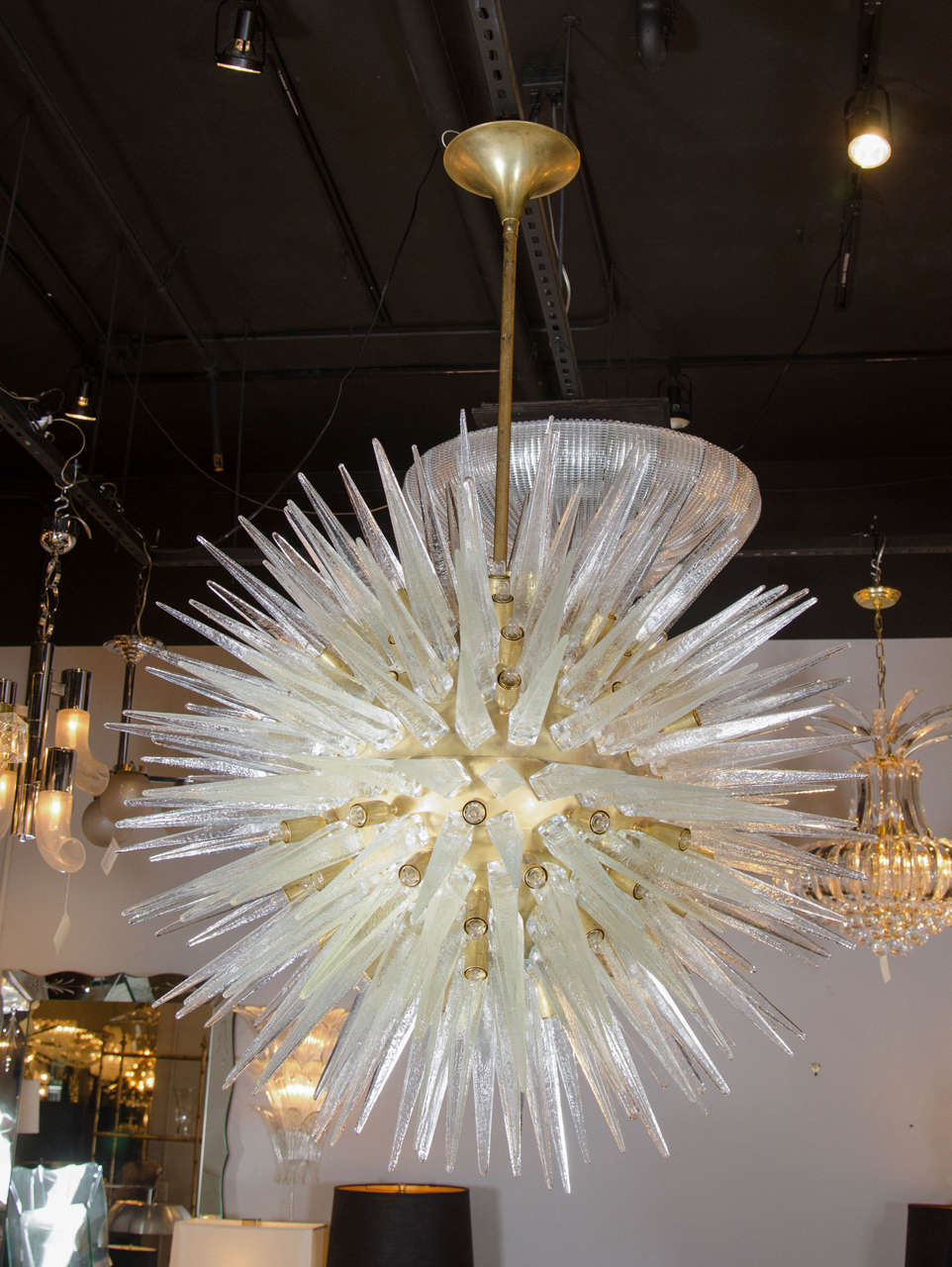 This important Mid-Century Modern sputnik chandelier features large handblown textured Murano glass spikes fixed directly to a large brushed brass central sphere. The chandelier has more than 80 bulbs and hangs from a rod which can be adjusted to