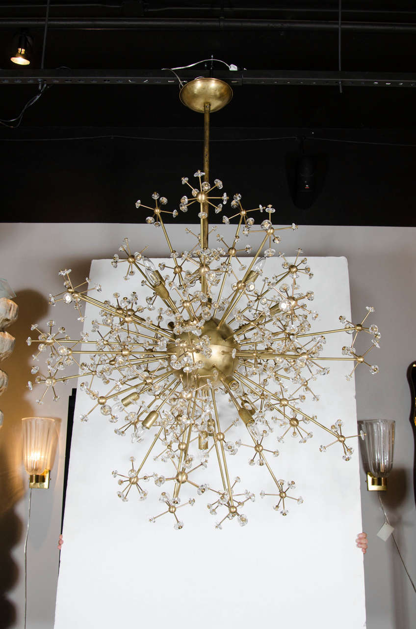 This stunning Mid-Century Modernist chandelier features a Sputnik design emanating from a central sphere in brushed brass. Each stem varies in length and ends with a small ball with branches stemming from them with clear Murano glass adornments