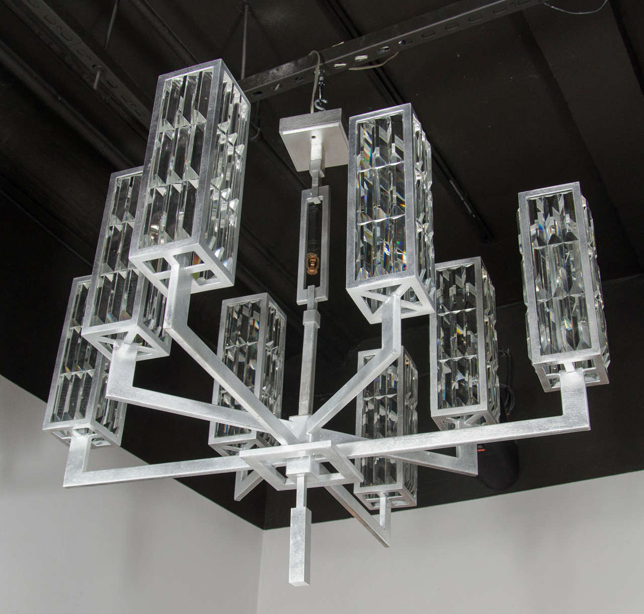 Elegant Modernist 8 arm chandelier with a silver leafed frame and architectural form. This chandelier features 8 total elongated, cubed shades that are comprised of thirty-six cut crystals each and have alternating stylized geometric supports that