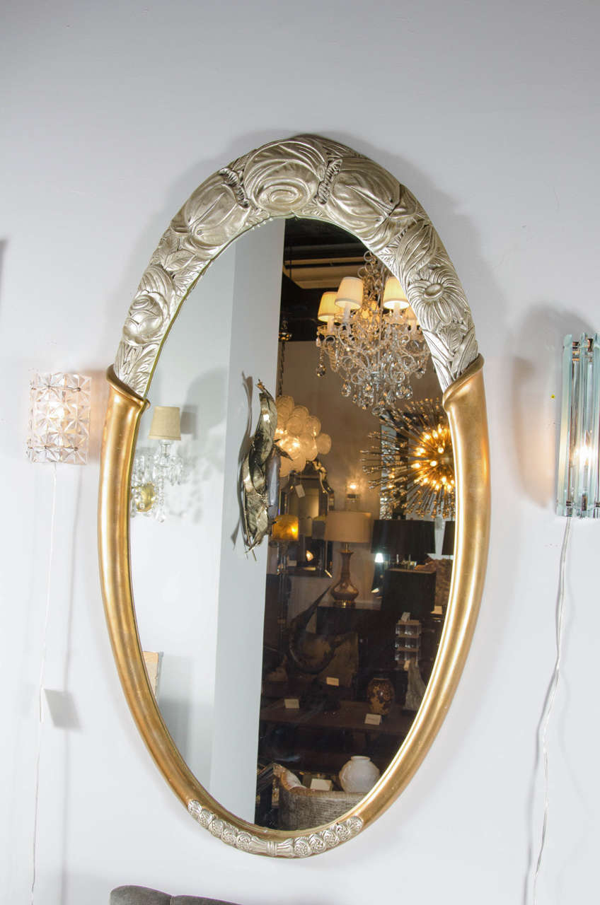 This gorgeous oval form mirror features a 24k gilt border with white gold stylized Art Deco foliage design.