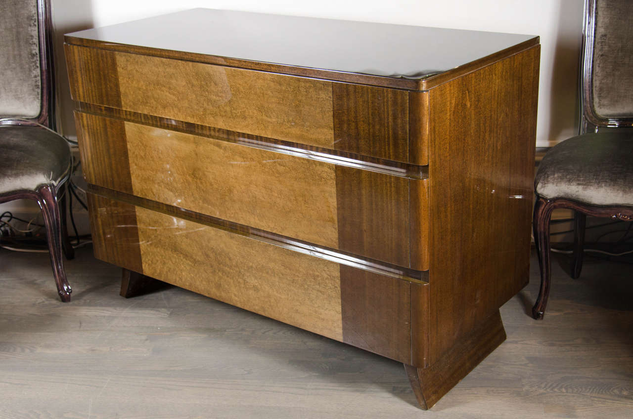This handsome chest of drawers was realized in the United States, circa 1940, by Rway Furniture Co. in the manner of Eliel Saarinen. It is composed of book-matched mahogany with exotic elm inlays; splayed legs; and three spacious drawers offering