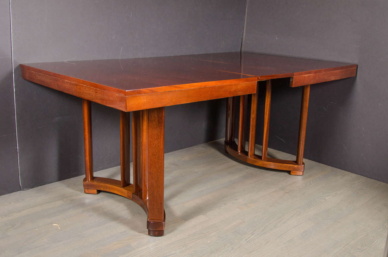 This outstanding Art Deco Extension Dining Table in book-matched mahogany features an arc form base in an opposing position with three central support rods at each end. It comes complete with one 12